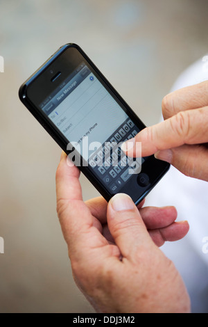 Senior man using Apple iphone 5 to write email Stock Photo