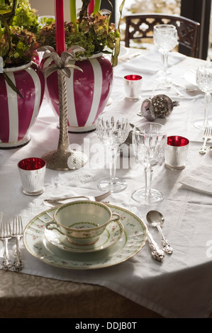 Place setting with Bernadaud Artois china on dinner table decorated with striped pink ginger jars Stock Photo
