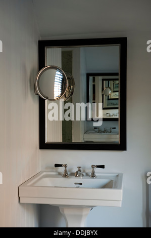 Hand basin with nickle taps and nickle circular mirror Stock Photo