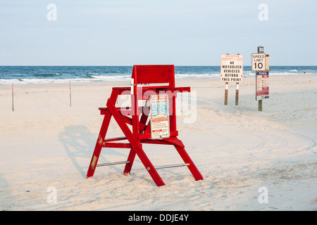 Unmanned red lifeguard station next to sign warning of no motorized traffic on Daytona Beach, Florida Stock Photo