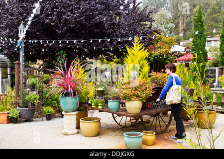 Middle-aged woman browsing a nursery amongst a collection of lush plants in Cambria, California Stock Photo