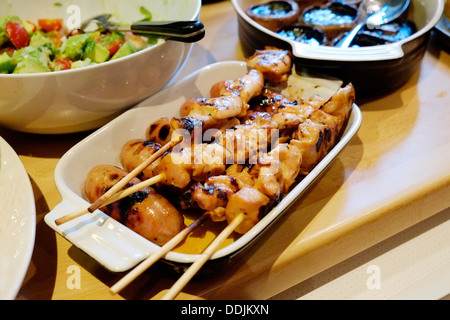 A delicious platter of Barbequed chicken on skewers with Barbequed mushrooms and avocado tomato salad in the background. Stock Photo
