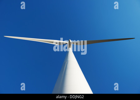 A wind turbine taken from below against blue sky Stock Photo