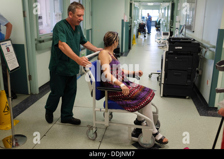 A hospital porter helping a woman being discharged from a NHS hospital in a wheelchair after a hip replacement operation UK Stock Photo