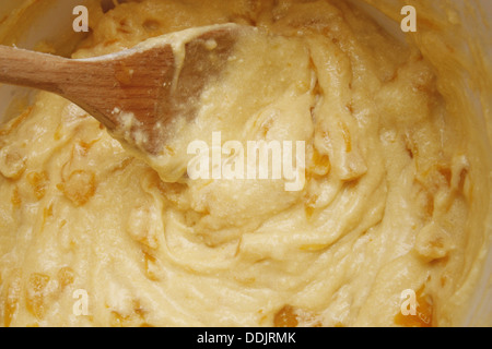 peach cupcake batter in white mixing bowl with wooden spoon Stock Photo