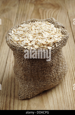 Oat flake in a sack on a wooden table Stock Photo