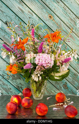 bright summer still life bouquet: hosta, astilbe, orange hemerocallis, pink hydrangea and nectarines Stock Photo
