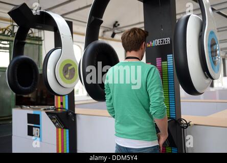 Berlin, Germany. 4th Sep, 2013. A man stands between giant sets of headphones listening to music at the Postbahnhof venue in Berlin, Germany, 4 September 2013. The Berlin Music Week takes place from 4 September to 8 September 2013. Photo: Britta Pedersen/dpa/Alamy Live News Stock Photo