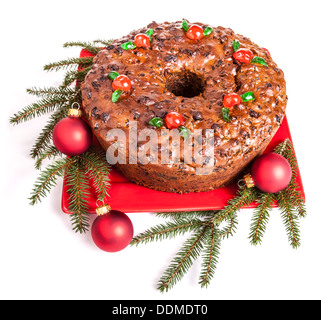 Traditional homemade Christmas fruitcake decorated with candied cherries, boughs and baubles Stock Photo
