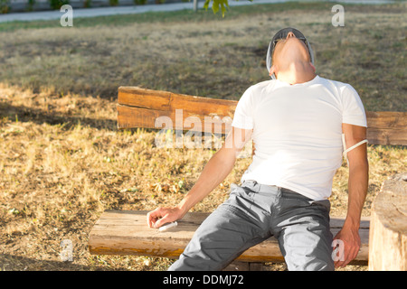 Middle-aged man experiencing euphoria after using psychoactive drugs sitting on a bench in the park Stock Photo