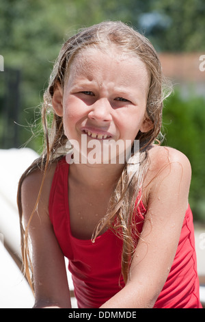 portrait of wet little caucasian girl in red swimsuit looking at camera Stock Photo