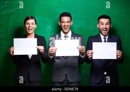 Elegant business partners with blank papers looking at camera on green background Stock Photo