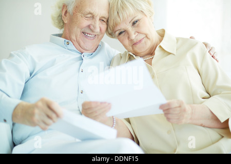 Portrait of happy senior couple reading letter together Stock Photo