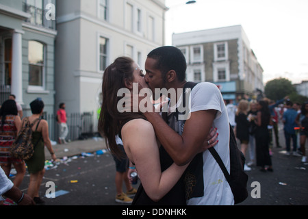 A couple kisses in the street in the dying light of the carnival. The show is over and the street party is starting. Stock Photo