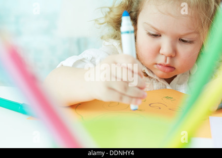 Blonde girl with serious expression drawing with felt-tip pens Stock Photo