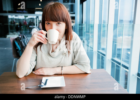 Woman drinking coffee in cup in a cafe Stock Photo