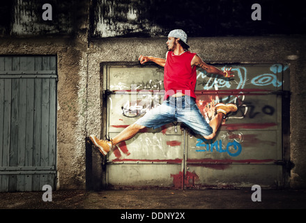 Young man / teen jumping / dancing on grunge graffiti wall background Stock Photo