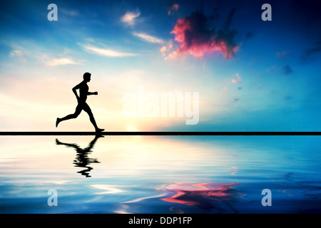 Silhouette of man running at sunset by water Stock Photo