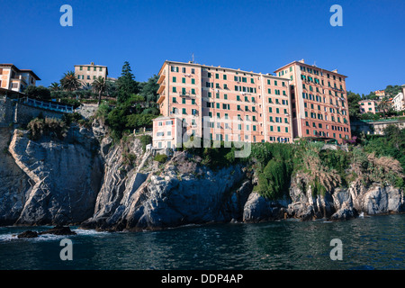 Houses built on the rocks overhanging sea in Liguria, Italy Stock Photo