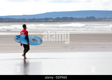 Surfer with surfboard walking on Enniscrone beach, Ireland Stock Photo