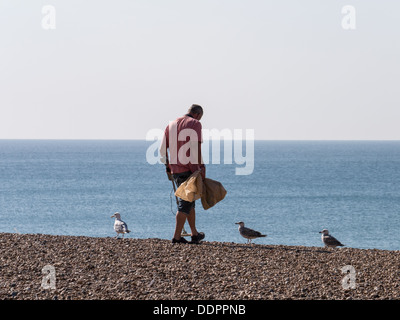 A man searches for treasure on the beach with a metal detector Stock Photo