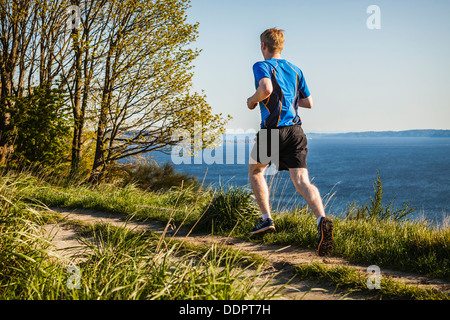 A young man running down stair steps on a trail in Discovery Park, Seattle, Washington, USA. Stock Photo