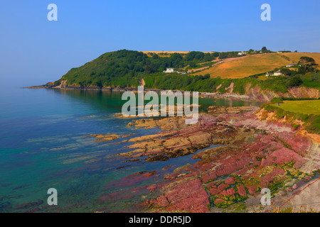 Colourful deep red rocks Talland Bay between Looe and Polperro Cornwall England UK on a beautiful blue sky sunny day in HDR Stock Photo