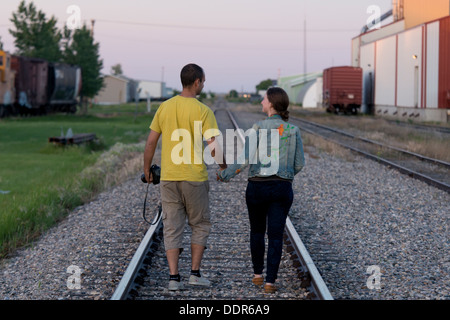 Couple walking between railroad tracks, Manitoba, Canada Stock Photo