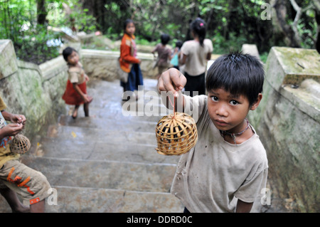 Local Lao Children selling a wish bird to free for US $1 to tourists at Pak Ou Cave in Luang Prabang, Laos. Stock Photo
