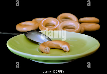 Tiny delicious bagels on a plate isolated on black. Russian sushki, dessert for tea ceremony Stock Photo