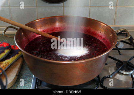 Preserving sugar being poured into a pan with fruit for jam making Stock Photo