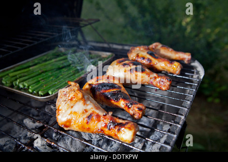 Chicken drumsticks on a grill, with asparagus Stock Photo