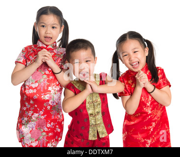 Little oriental children wishing you a happy Chinese New Year, with traditional Cheongsam standing isolated on white background. Stock Photo