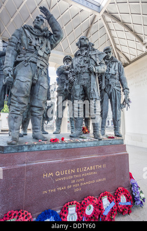 RAF Bomber Command Memorial, Green Park, London, England with statues of heroic airmen of WWII and red and blue poppy wreaths laid around base