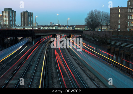Trains enter and leave a train station below a new moon Stock Photo