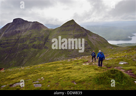 Two male walkers on western ridge of Sail Gharbh (a Corbett) on the Scottish mountain Quinag heading towards Spidean Coinich Stock Photo