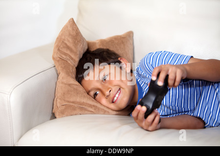 Young boy playing computer game while relxing on the sofa Stock Photo