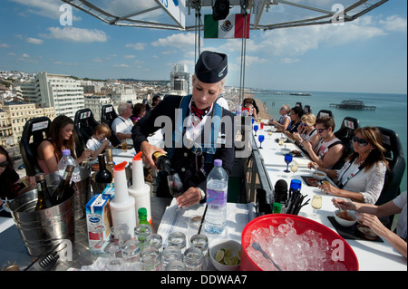 A British Airways Stewardess serves drinks to diners 100 foot high in the sky above Brighton and Hove beach as part of 'BA Goes Beachside'. They are seated at a dining table hoisted up by a crane. Stock Photo