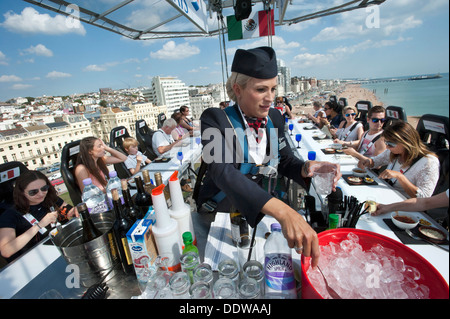 British Airways Ambassador Stewardess Purser Laura Ross serves drinks to 22 diners 100 foot high in the sky above Brighton and Hove beach on a dining table in the sky Stock Photo