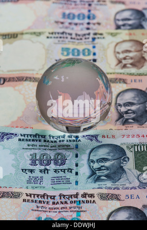 Crystal Glass globe showing India on Rupee notes Stock Photo