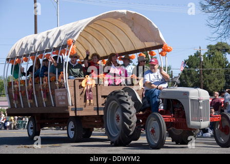 Hayride fun: people in a covered wagon trailer pulled by tractor laughing and waving, Ellensburg Rodeo Western Parade, WA, USA Stock Photo