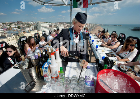 A British Airways Ambassador Stewardess Purser serving drinks to 22 diners 100 foot high in the sky above Brighton and Hove beach on a dining table in the sky. Stock Photo