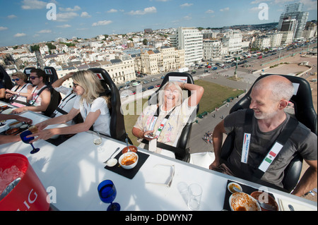 Laughing woman pensioner enjoying an adventure at a dining table 100 ft above the ground Stock Photo