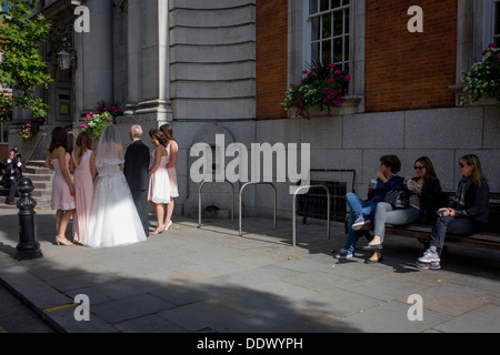 People watch a bride and bridesmaids from a civil wedding ceremony outside Chelsea Registry Office Stock Photo