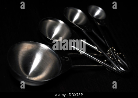 A set of kitchen measuring cups/spoons photographed against a black background. Stock Photo