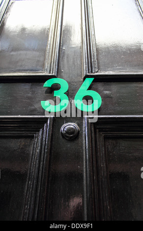The number 36 in Green numbering on a black door Stock Photo