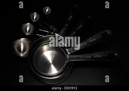 A set of kitchen measuring cups/spoons photographed against a black background. Stock Photo