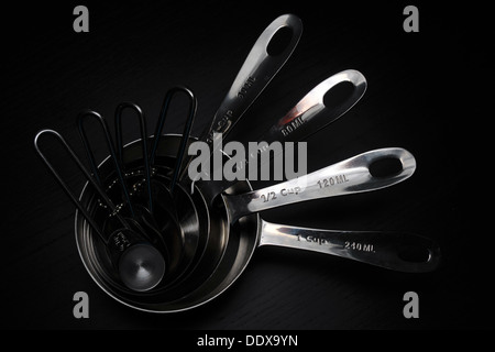 A set of kitchen measuring cups/spoons photographed against a black background. Stock Photo