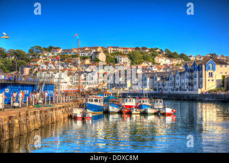 Brightly coloured boats Brixham harbour Devon with houses on hillside in background in HDR Stock Photo