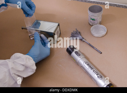 A CSI (Crime Scene Investigator) lifting off a fingerprint on a surface using adhesive tape. Stock Photo